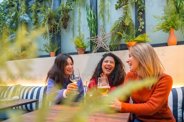 Focus on three adult women having fun drinking wine in a cafeteria