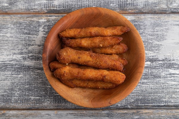 Chicken nuggets on a wooden plate on a gray wooden background. Top view, flat lay, close up