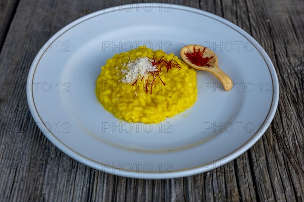 Elegant Plate with Risotto alla Milanese with Saffron and Parmesan Cheese on an Old Wood Table in Lugano, Ticino, Switzerland, Europe
