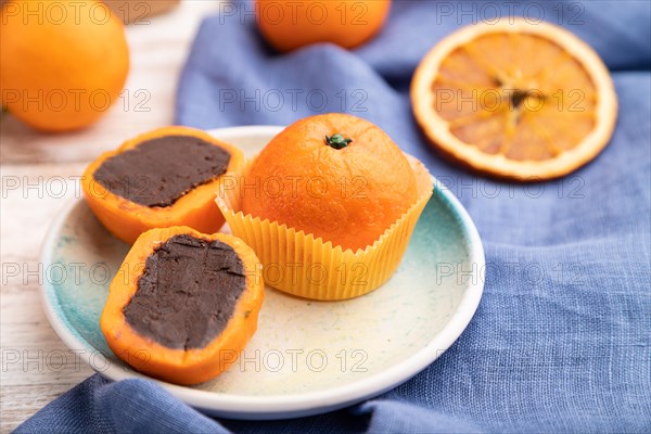 Truffle chocolate tangerine candies on a white wooden background and blue linen textile. Side view, close up, selective focus