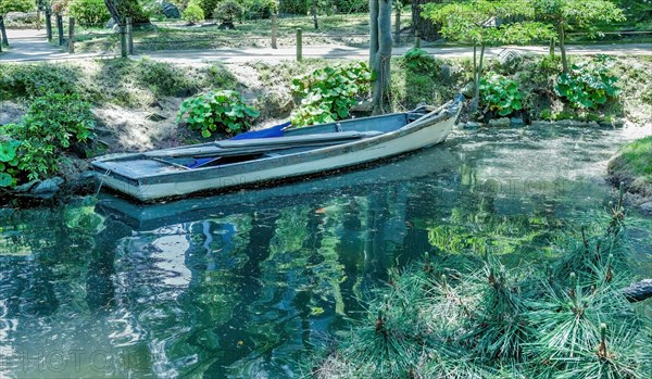 Wooden row boat at shore of lake in Japanese Shukkeien Gardens in Hiroshima, Japan, Asia