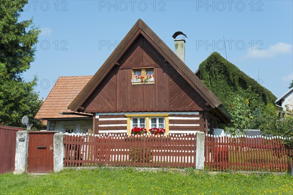 Small cottage with a red roof and white shutters, surrounded by a garden and a wooden fence, Old wooden house, Vesec u Sobotky, village conservation area, Liboovice, Okres Jicin, Hradec Kralove, Czech Republic, Europe