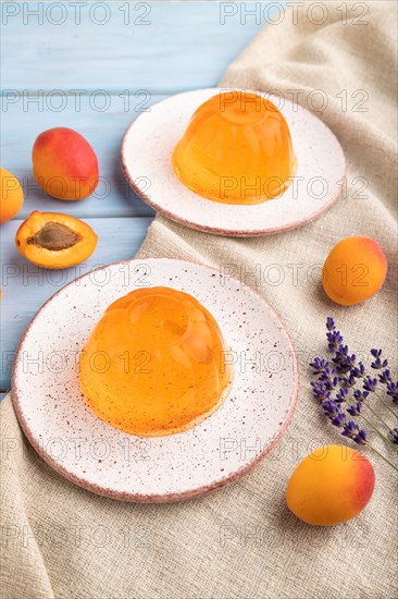 Apricot orange jelly on blue wooden background and linen textile. side view, close up