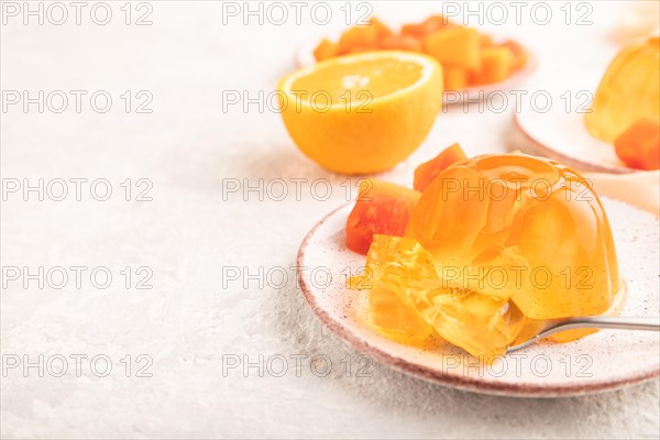 Papaya and orange jelly on gray concrete background and orange linen textile. side view, flat lay, close up, selective focus