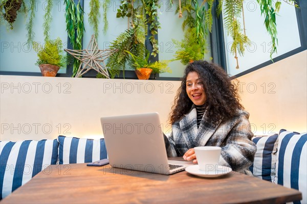 Young female entrepreneur working with laptop in a cafeteria using laptop and drinking coffee