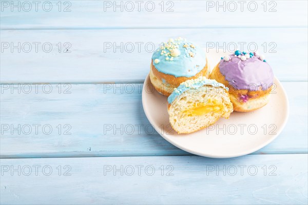Purple and blue glazed donut on blue wooden background. side view, copy space. Breakfast, morning, concept