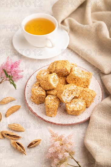 Traditional turkish delight (rahat lokum) with cup of green tea on a gray concrete background and linen textile. side view, close up