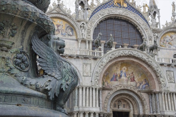 Old street ornament with winged lions and San Marco Basilica in the background, in St. Mark Square, famous tourist attraction in Venice, Italy. Selective focus