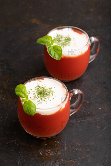 Tomato juice with basil and sour cream in glass on a black concrete background. Healthy drink concept. Side view, close up