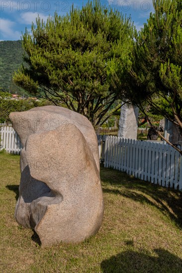 Large granite boulder in front of white picket fence in public rock garden in Gimcheon, South Korea, Asia