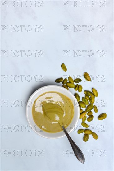 Pistachio cream in small bowls with spoon, pistachios