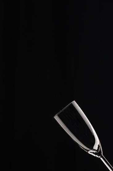 An empty champagne glass against a black background with clear lines