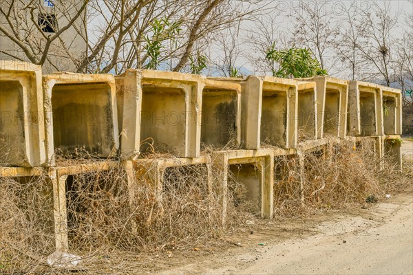 Square sections of concrete drainage culverts stacked beside paved rural road