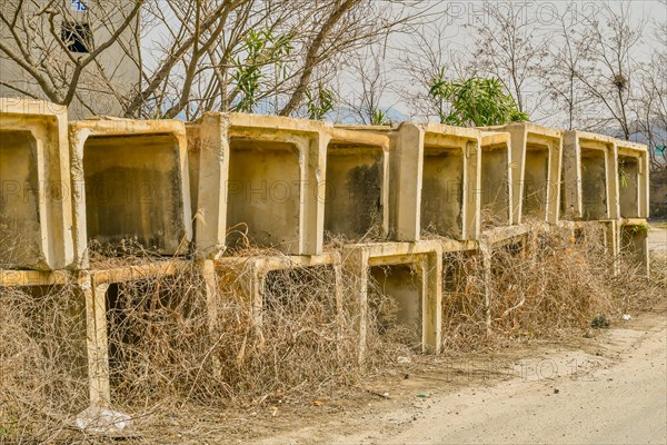 Square sections of concrete drainage culverts stacked beside paved rural road