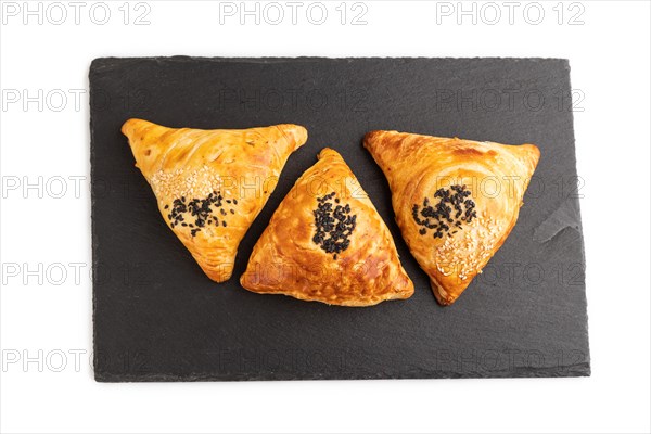 Homemade asian pastry samosa on black slate board isolated on white background. top view, flat lay, close up