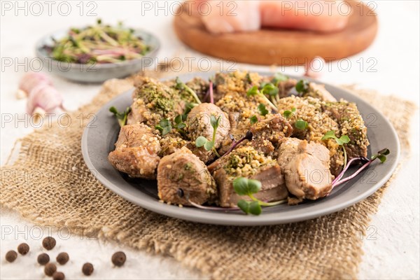 Stewed turkey fillet with garlic and sprouts of radish on white wooden background and linen textile. Side view, close up, selective focus