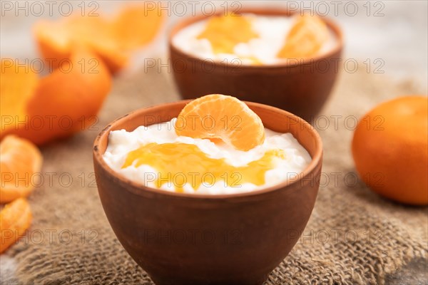 Grained cottage cheese with tangerine jam on brown concrete background and linen textile. side view, close up, selective focus