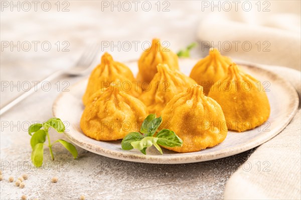 Fried manti dumplings with pepper, basil on gray concrete background and linen textile. Side view, close up, selective focus