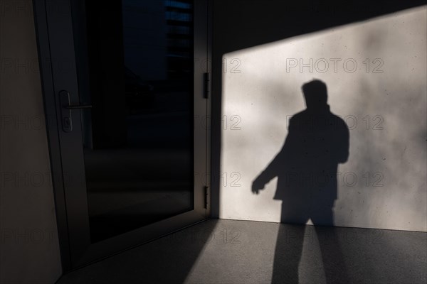 Shadow of a Man on the Concrete Wall and Entering in a Office Door in a Sunny Day in Switzerland