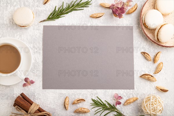 Gray paper sheet mockup with cup of coffee, almonds and macaroons on gray concrete background. Blank, business card, top view, flat lay, still life