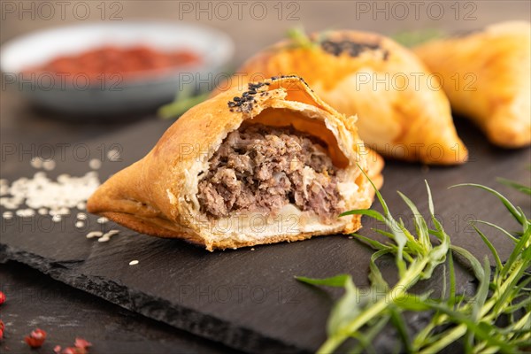 Homemade asian pastry samosa on black concrete background. side view, selective focus