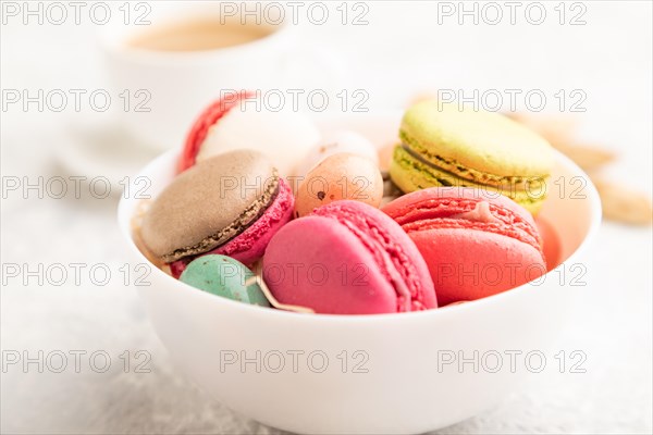 Multicolored macaroons and chocolate eggs in ceramic bowl, cup of coffee on gray concrete background. side view, close up, selective focus, still life. Breakfast, morning, concept