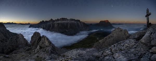 Summit cross of the large Cirrspitze with sunrise over a sea of fog and Dolomite peaks in the background, Corvara, Dolomites, Italy, Europe