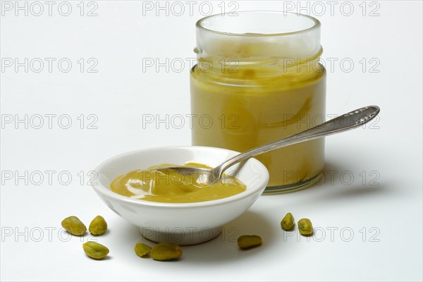 Pistachio cream in small bowls with spoon, pistachios