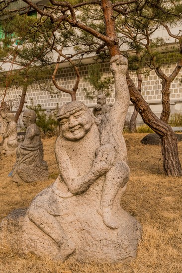 Stone carved statue of Buddhist deity in front of white wall in garden in South Korea