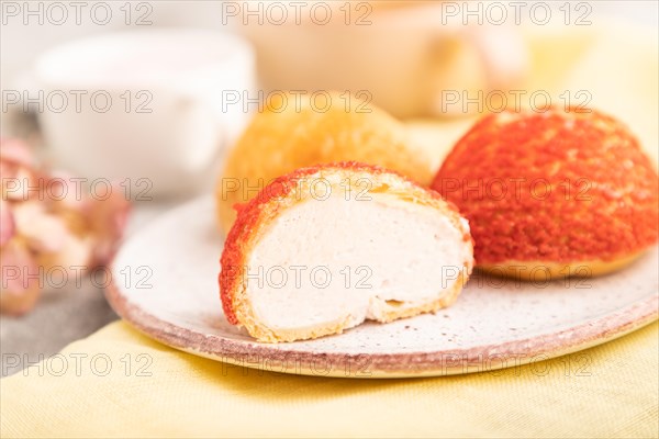 Traditional french custard dessert shu cake and cup of green tea on brown concrete background and yellow linen textile. side view, selective focus. Breakfast, morning, concept