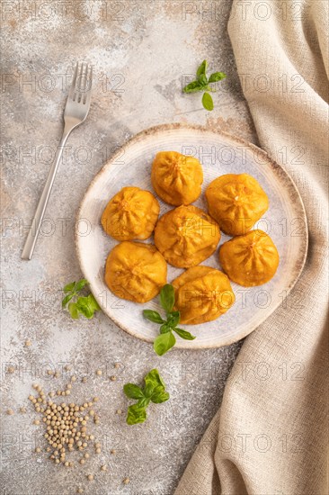 Fried manti dumplings with pepper, basil on gray concrete background and linen textile. Top view, flat lay, close up