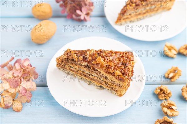Walnut and hazelnut cake with caramel cream, cup of coffee on blue wooden background. side view, copy space, selective focus
