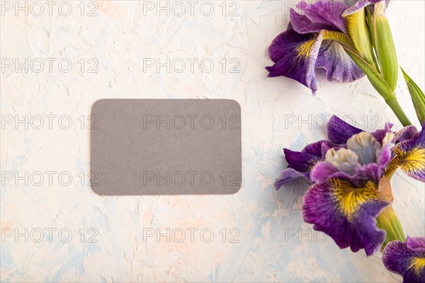 Gray business card with lilac iris flowers on white concrete background. top view, flat lay, copy space, still life. Breakfast, morning, spring concept