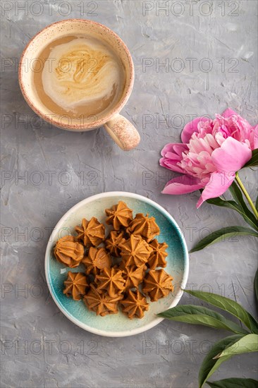 Homemade soft caramel fudge candies on blue plate and cup of coffee on gray concrete background, peony flower decoration. top view, flat lay, close up