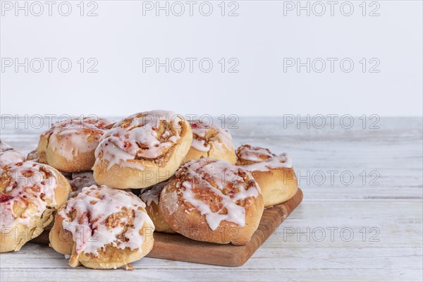 Fresh homemade cinnamon buns with icing on a wooden board, copy room