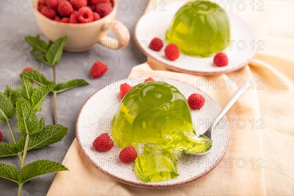 Mint and raspberry green jelly on gray concrete background and orange linen textile. side view, close up, selective focus