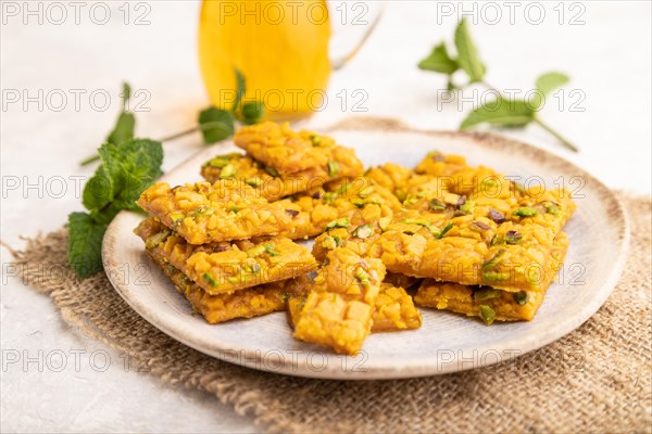 Traditional iranian dessert sohan with glass of green tea on a gray concrete background and linen textile. side view, close up, selective focus