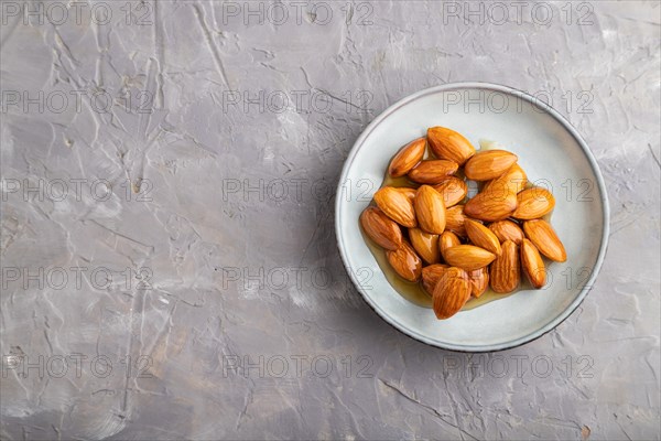 Almonds with honey on gray concrete background. top view, flat lay, close up, copy space