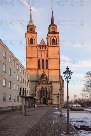 The twin towers of St John's Church rise into the evening sky, surrounded by snow and a street lamp, Magdeburg, Saxony-Anhalt, Germany, Europe
