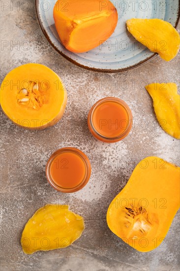 Baby puree with fruits mix, pumpkin, persimmon, mango infant formula in glass jar on brown concrete background. Top view, flat lay, close up, artificial feeding concept