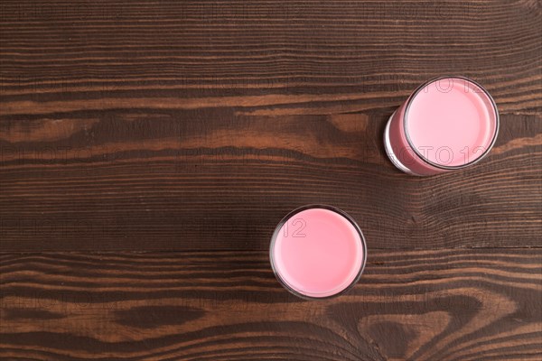 Sweet strawberry liqueur in glass on a brown wooden background. top view, copy space, flat lay