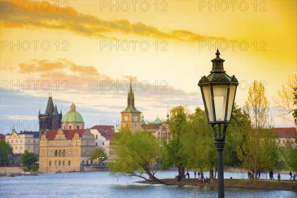 Blurred view of Strelecky island on Vltava river and old town of Prague, Czech Republic, at sunset. Selective focus on the street light, Europe