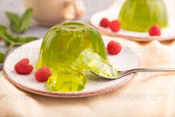 Mint and raspberry green jelly on gray concrete background and orange linen textile. side view, close up, selective focus