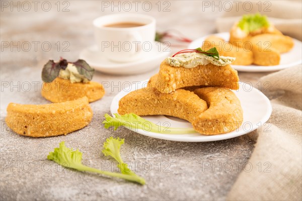 Homemade salted crescent-shaped cheese cookies, cup of coffee on brown concrete background and linen textile. side view, close up, selective focus