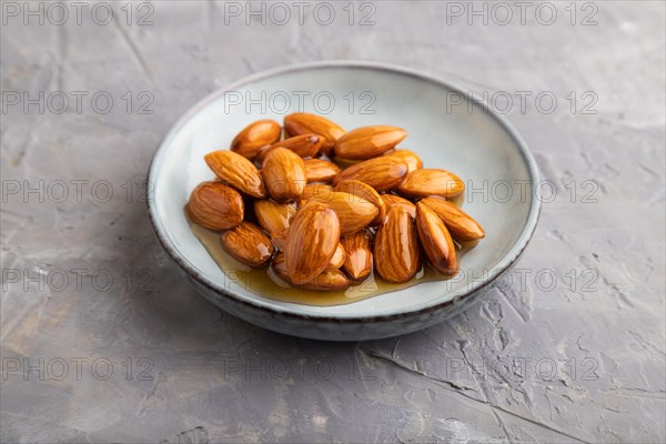 Almonds with honey on gray concrete background. side view, close up