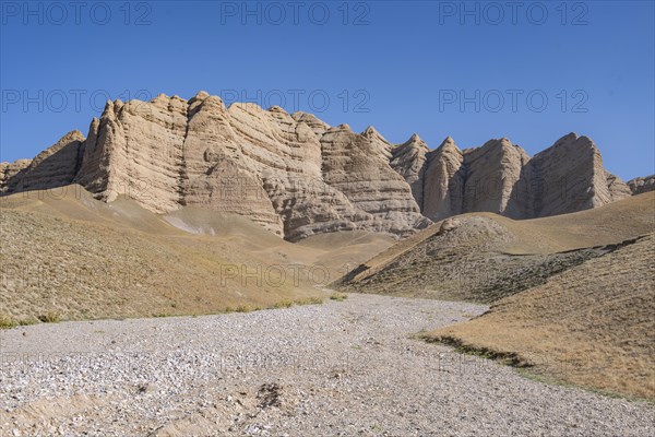 Mountain landscape with steep rocks, eroded rock formations between yellow hills, near Baetov, Naryn region, Kyrgyzstan, Asia