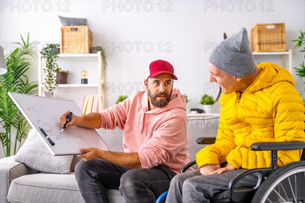 Man teaching economy to a disabled man drawing a graphic in a white board at home