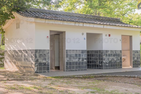 Public restrooms in shaded area of urban park in Hiroshima, Japan, Asia
