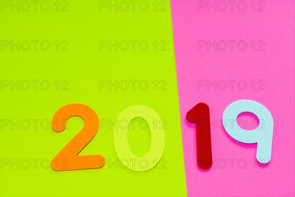 The numbers 2019 made of felt of different colors photographed on pink and yellow background