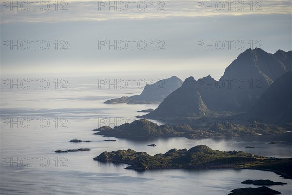 View of the coast in Ulvagsundet fjord and mountains in the evening light, Hurtigruten cruise ship in the fjord, view from the summit of Dronningsvarden or Stortinden, Vesteralen, Norway, Europe